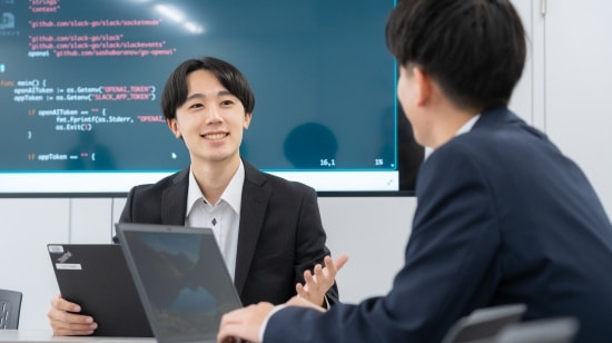 写真 パソコンの前で打ち合わせをするスーツの男女