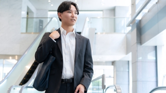 写真 パソコンの前で相談するスーツの男女